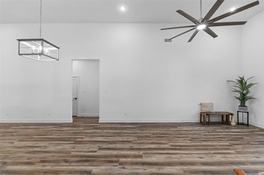 Spare room featuring ceiling fan with notable chandelier, vaulted ceiling, and hardwood / wood-style flooring