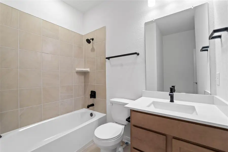 The secondary bathroom showcases tile flooring, a bath/shower combo with Daltile tile surround, a vanity with stunning light countertop, a mirror, sleek fixtures, and contemporary finishes throughout. The secondary bathroom showcases tile flooring, a bath/shower combo with Daltile tile surround, a vanity with stunning light countertop, a mirror, sleek fixtures, and contemporary finishes throughout.