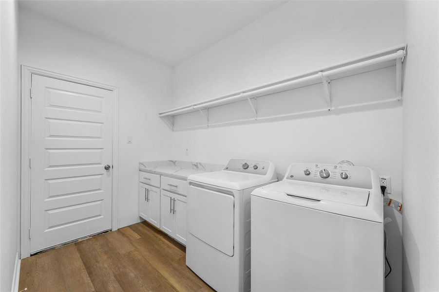 Utility room featuring wood-finish flooring, white cabinetry with silver hardware, and a white countertop