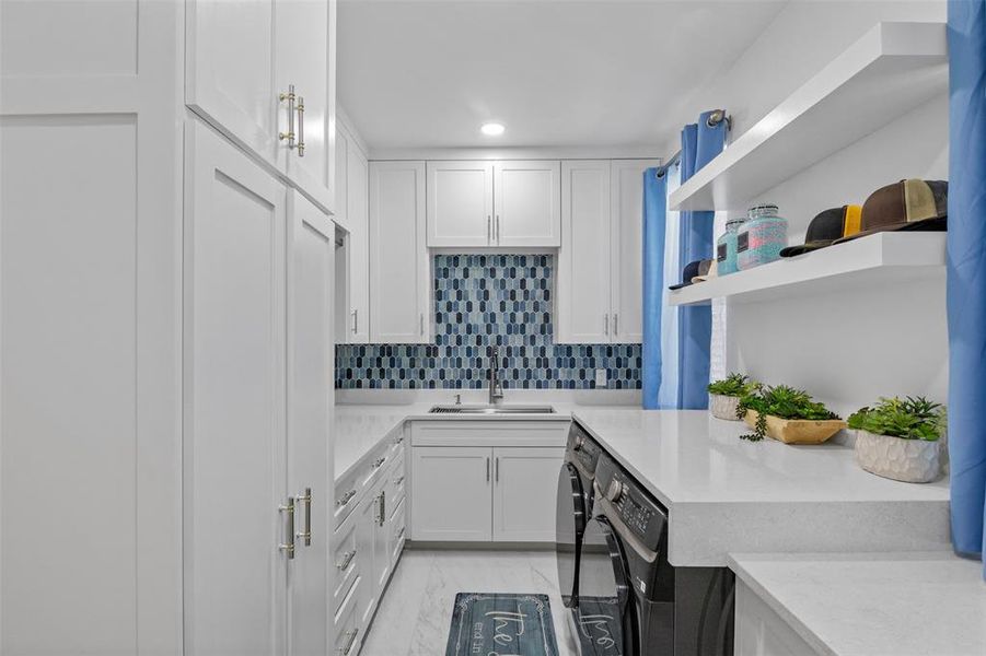 Kitchen featuring white cabinets, light stone counters, open shelves, backsplash, and washing machine and dryer Kitchen featuring white cabinets, light stone counters, open shelves, backsplash, and washing machine and dryer