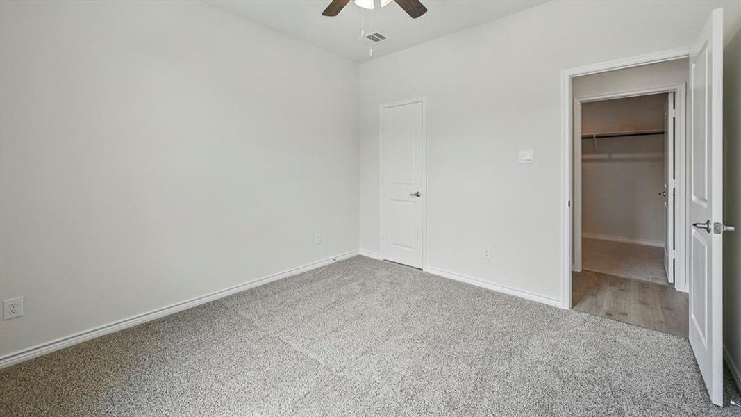 Unfurnished bedroom featuring carpet floors, a spacious closet, and ceiling fan
