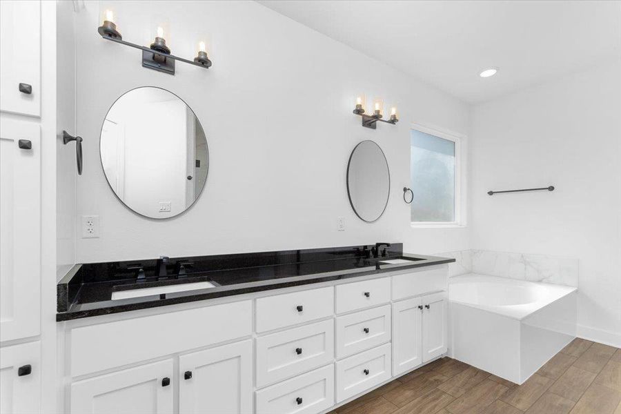 Full bathroom with double vanity, wood finished floors, a bath, and recessed lighting Full bathroom with double vanity, wood finished floors, a bath, and recessed lighting