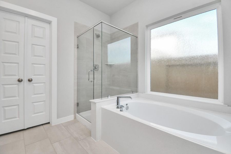 Indulge in a spa-like retreat within the confines of this primary bathroom. Delight in a spacious walk-in shower enveloped in stylish tile surround and unwind in a separate garden tub adorned with custom detailing.