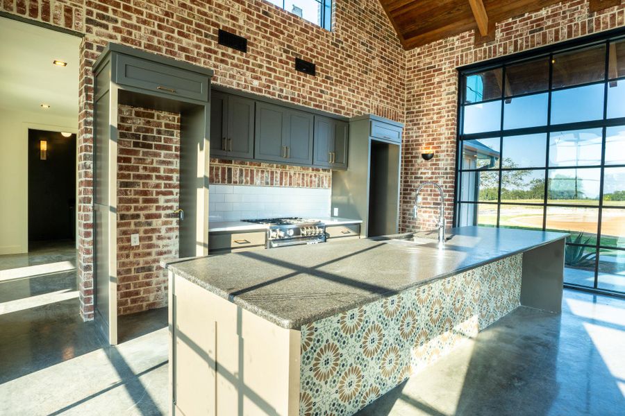 Kitchen with brick wall, high vaulted ceiling, plenty of natural light, concrete flooring, and wood ceiling
