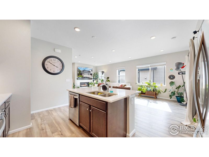 Spacious kitchen featuring stainless steel appliances, a gas range and oven, quartz countertops including a kitchen island and a custom tile backsplash.