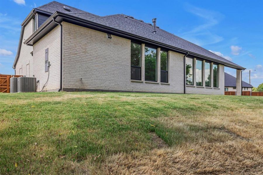 Back of property with a lawn and central AC unit