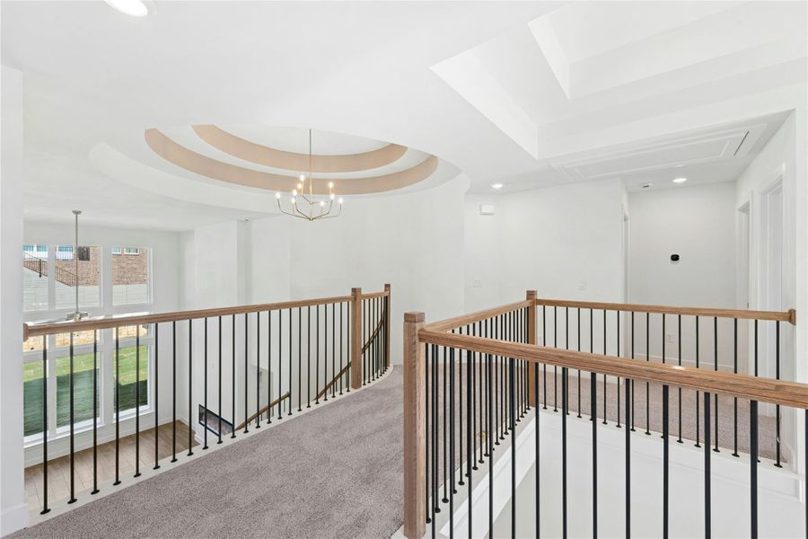 Hallway featuring an upstairs landing, a raised ceiling, carpet floors, recessed lighting, and a chandelier