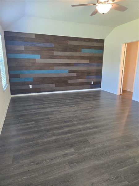 Unfurnished room with ceiling fan, lofted ceiling, and wood-type flooring