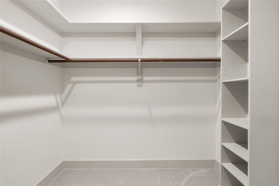 Walk-in primary closet with hanging rails and built-in shelving Walk-in primary closet with hanging rails and built-in shelving