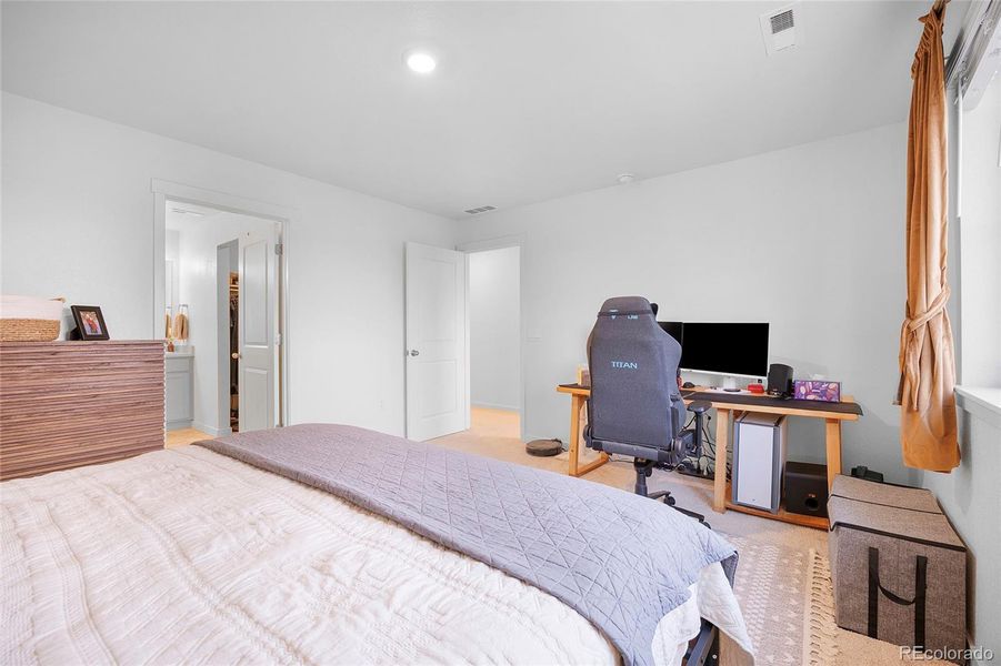The primary bedroom is a large room with natural light that flows through. Door to left is the bathroom