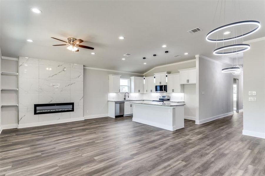 Kitchen with a kitchen island, a tiled fireplace, and ornamental molding