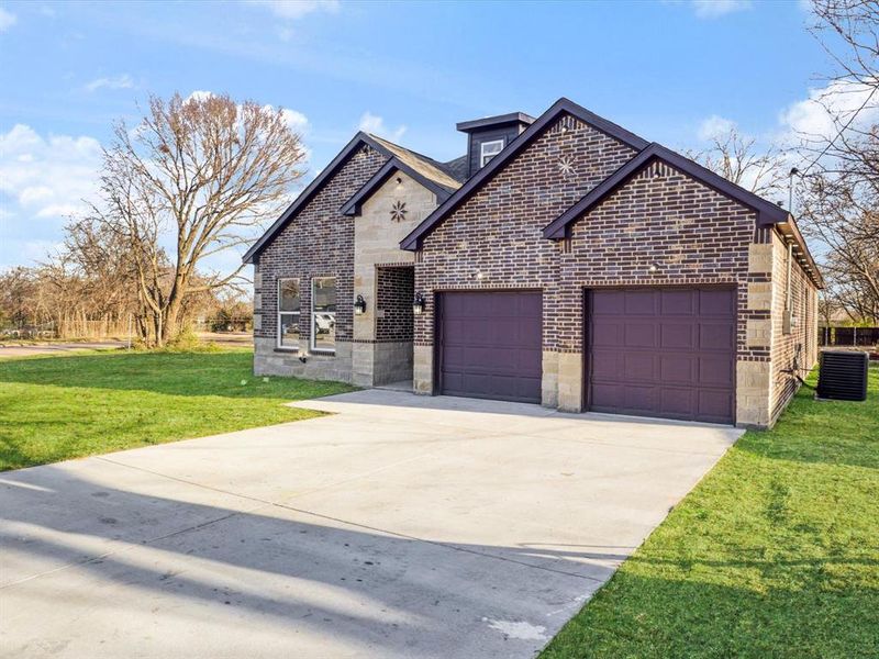 French country style house featuring brick siding, a front yard, an attached garage, concrete driveway, and stone siding French country style house featuring brick siding, a front yard, an attached garage, concrete driveway, and stone siding