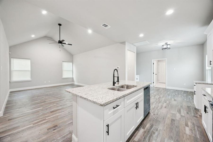 Kitchen with white cabinetry, recessed lighting, granite countertops, open floor plan, and vaulted ceiling