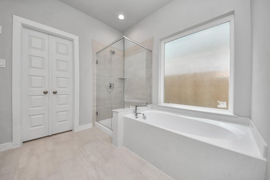 Indulge in a spa-like retreat within the confines of this primary bathroom. Delight in a spacious walk-in shower enveloped in stylish tile surround, unwind in a separate garden tub adorned with custom detailing.