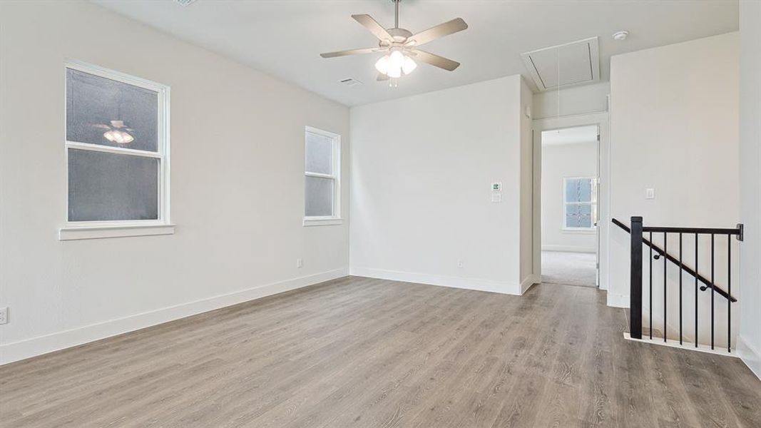 Spacious room with wood-finish flooring, two windows, and a ceiling fan