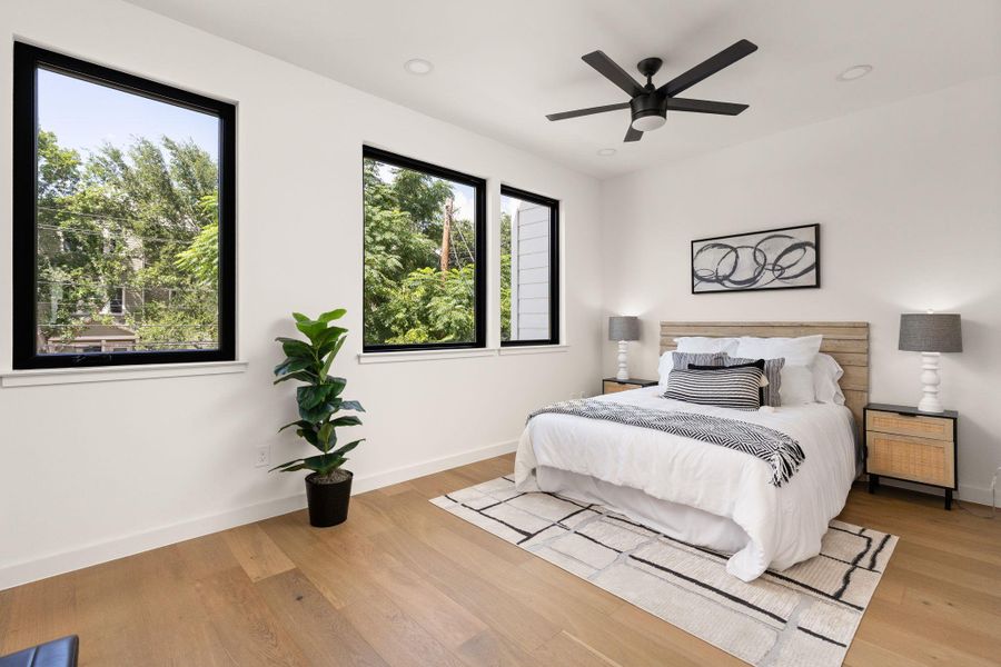 Natural light streams into this serene bedroom, highlighting light wood flooring and modern recessed lighting.