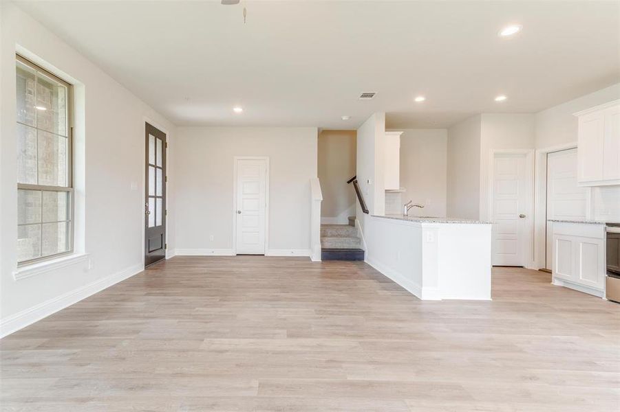 Kitchen featuring white cabinetry, sink, light stone countertops, and light hardwood / wood-style floors