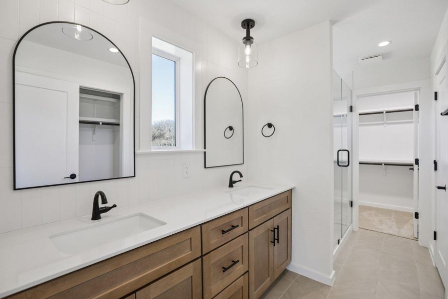 Bathroom featuring a walk in closet, double vanity, recessed lighting, a shower stall, and light tile patterned flooring