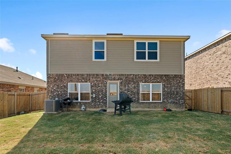 Back of property with a fenced backyard and brick siding