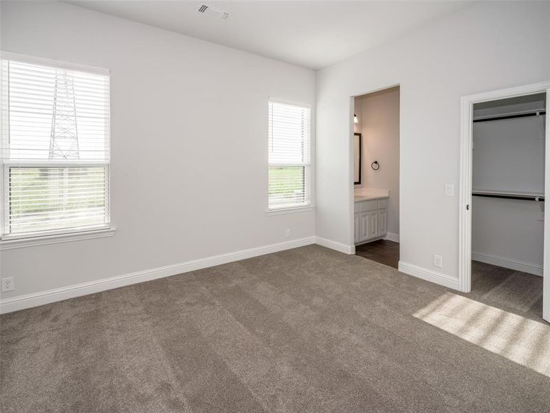 Unfurnished bedroom featuring dark carpet, a spacious closet, and ensuite bathroom