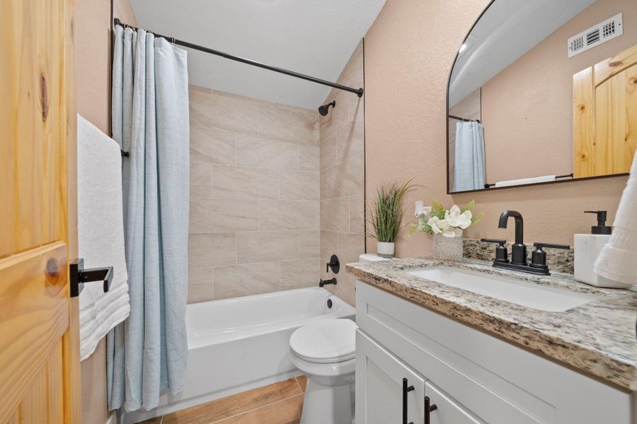 Full secondary bathroom with showing/tub combo and con=mfortable sink.