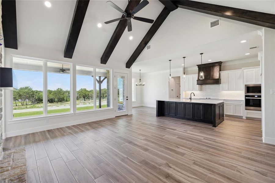 Unfurnished living room with light hardwood / wood-style floors, sink, ceiling fan, and beamed ceiling