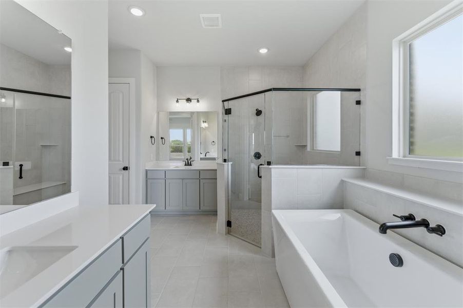 Bathroom featuring a shower stall, two vanities, a garden tub, recessed lighting, and light tile patterned flooring