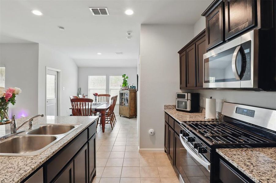 Kitchen with light tile patterned flooring, a sink, stainless steel appliances, visible vents, and recessed lighting