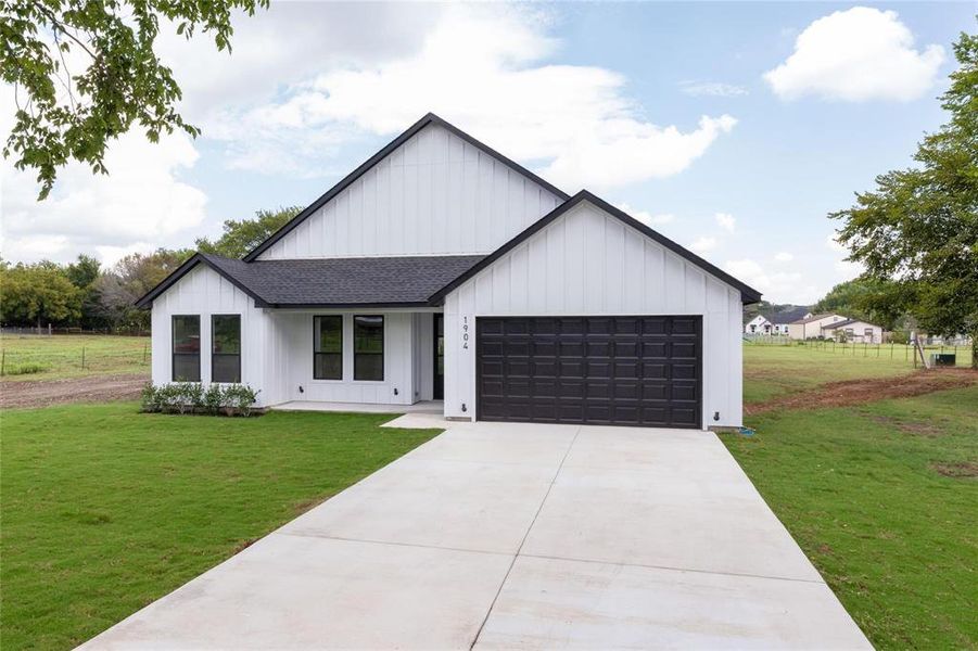 Modern farmhouse style home with a front yard and a garage