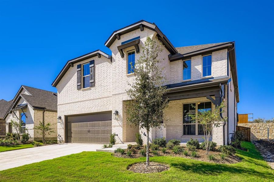 View of front facade featuring brick siding, covered porch, an attached garage, and driveway