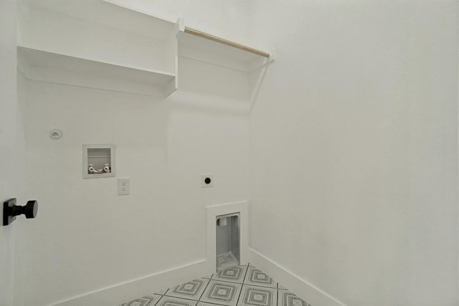 Laundry area featuring white walls, built-in shelving, a wooden hanging rod, and patterned tile flooring Laundry area featuring white walls, built-in shelving, a wooden hanging rod, and patterned tile flooring