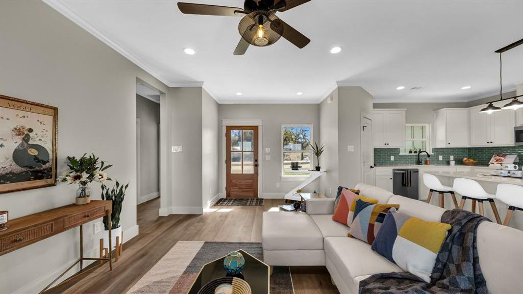 Living room with ornamental molding, recessed lighting, ceiling fan, and light wood-type flooring