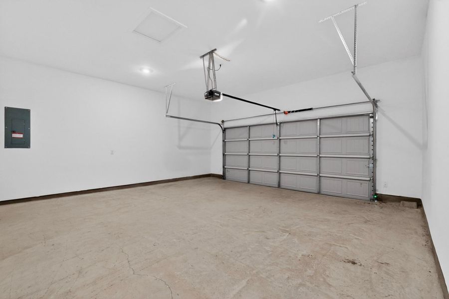 Spacious garage featuring a concrete floor, white walls, and a panel-style overhead door