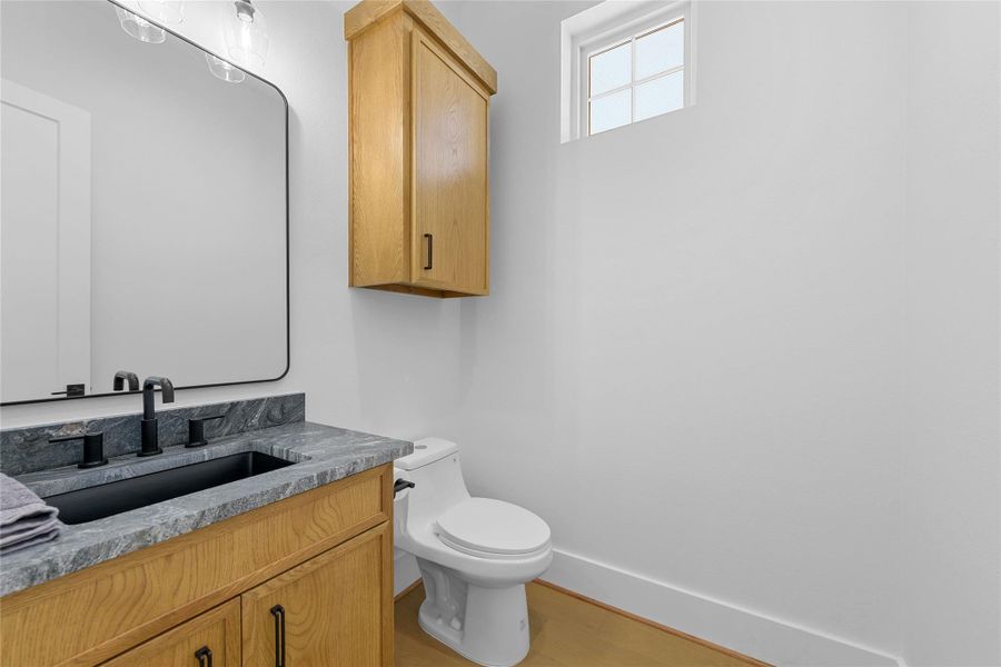 This stylish full bath features sleek gold hardware, elegant lighting, and a herringbone-tiled shower wall with built-in niche. A sophisticated space that perfectly blends function and design for guests or everyday use.