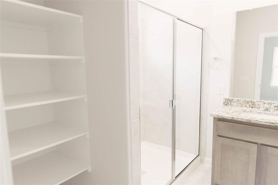 Bathroom featuring vanity and a shower with door