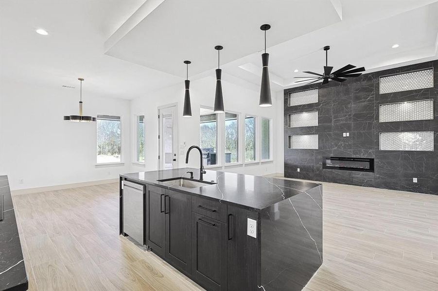 Kitchen with stainless steel dishwasher, plenty of natural light, sink, a center island with sink, and hanging light fixtures