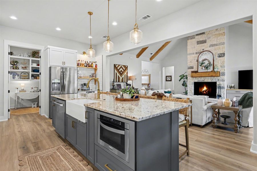 Kitchen featuring gray & white cabinets, decorative light fixtures, LVP floors, light stone counters, recessed lighting with bar area and walk-in prep pantry