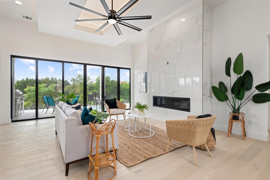 Photo is similar to the home being built. Decorative tray ceiling, recessed gas fire place, expansive patio doors and hardwood floors.