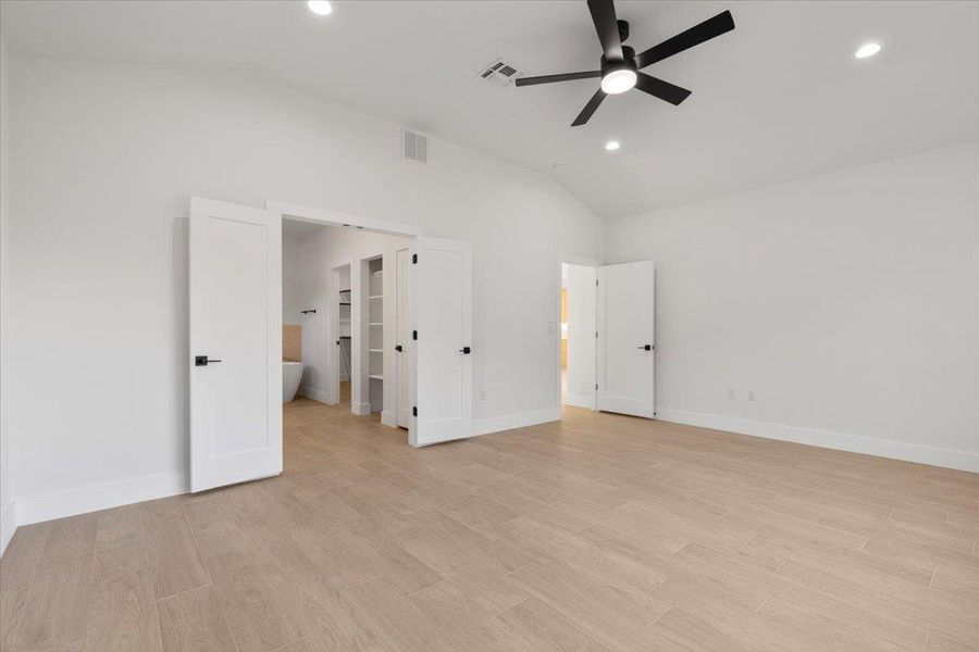 Unfurnished bedroom with lofted ceiling, light wood-type flooring, recessed lighting, ceiling fan, and ensuite bathroom Unfurnished bedroom with lofted ceiling, light wood-type flooring, recessed lighting, ceiling fan, and ensuite bathroom