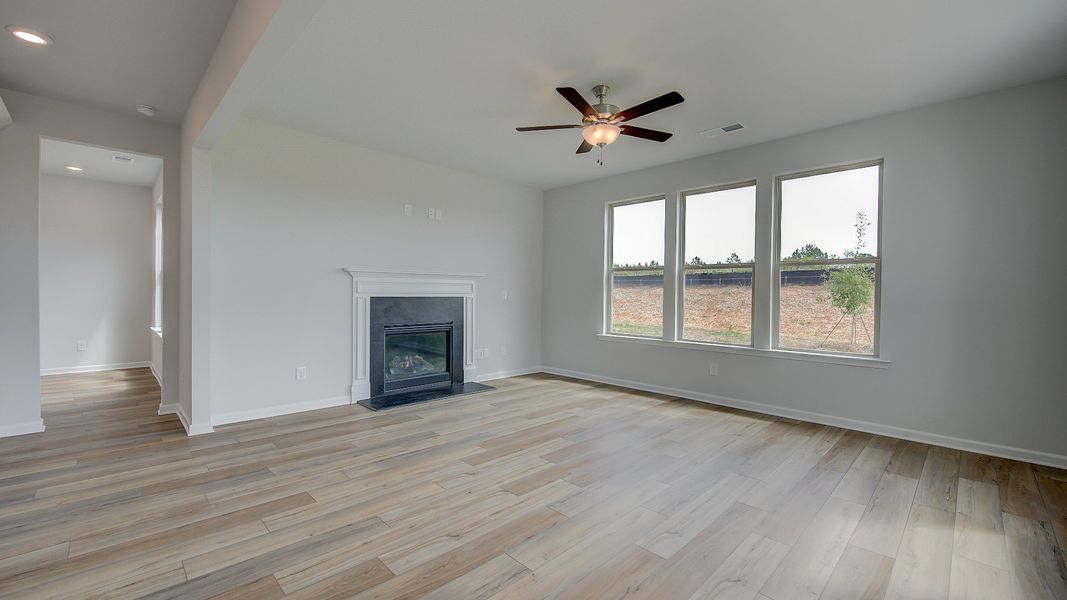 Stonefield open-concept family room with gas fireplace, LVP flooring, and connection to kitchen at Brighton.