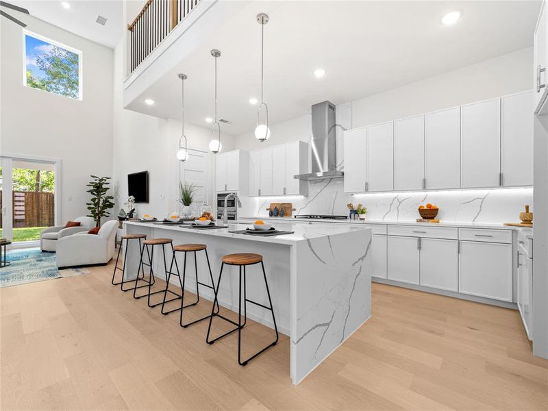 Kitchen with tasteful backsplash, recessed lighting, a kitchen breakfast bar, light wood-style floors, and white cabinets