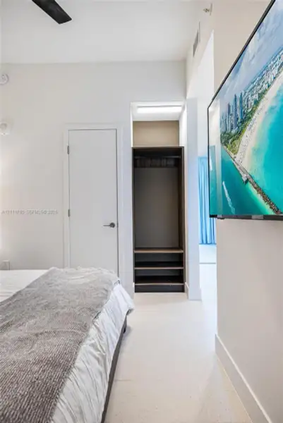 Built-in closet with integrated shelving, ceiling-mounted fan, and tile flooring