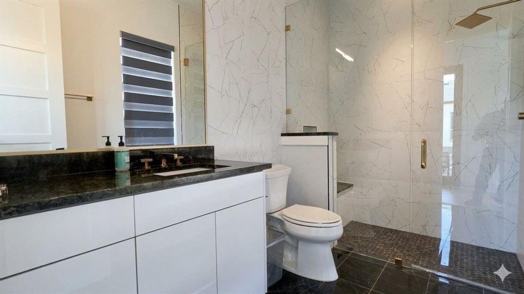Bathroom featuring a floating vanity with dark countertop, integrated sink, and wall-mounted faucet