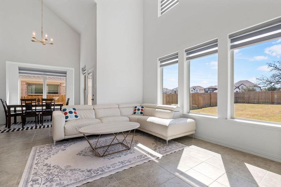 Living area featuring a high ceiling and hanging lights Living area featuring a high ceiling and hanging lights