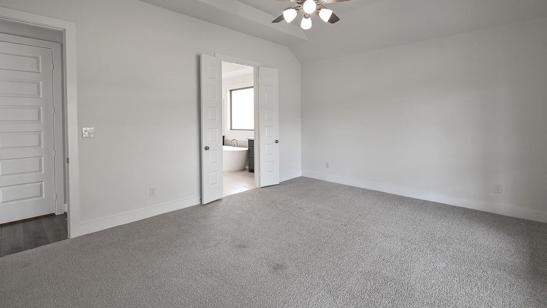 Unfurnished bedroom featuring carpet floors, connected bathroom, a ceiling fan, and vaulted ceiling Unfurnished bedroom featuring carpet floors, connected bathroom, a ceiling fan, and vaulted ceiling