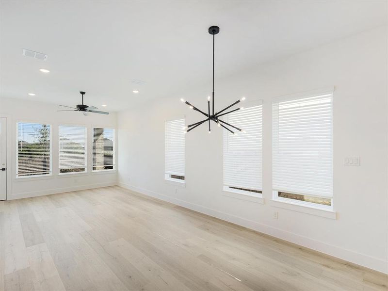 Unfurnished dining area featuring light wood-style flooring, a chandelier, ceiling fan, and recessed lighting Unfurnished dining area featuring light wood-style flooring, a chandelier, ceiling fan, and recessed lighting