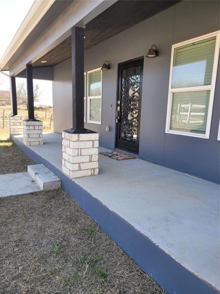 View of exterior entry with a porch and stucco siding