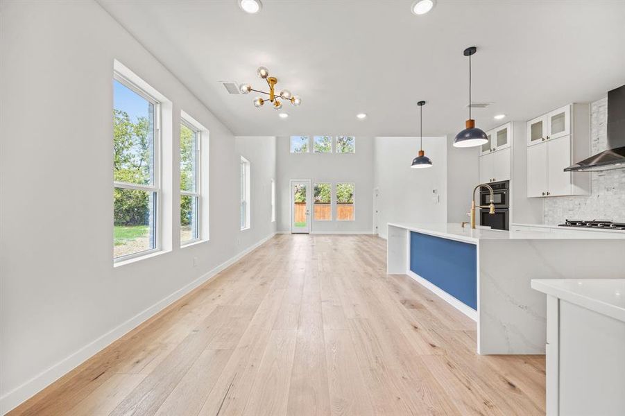 Kitchen with decorative backsplash, white cabinetry, light hardwood / wood-style flooring, and plenty of natural light