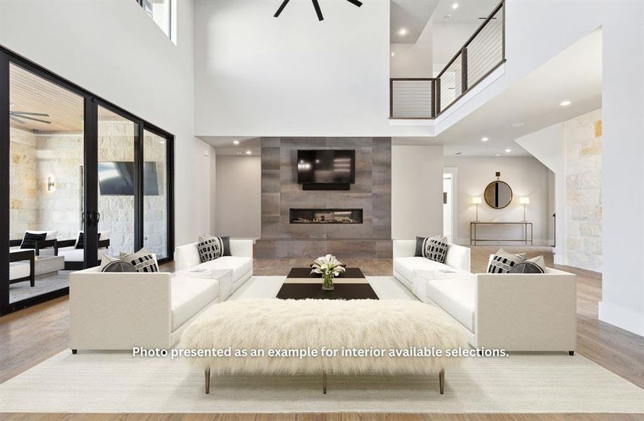 Living room featuring ceiling fan, a towering ceiling, a fireplace, and light wood-type flooring