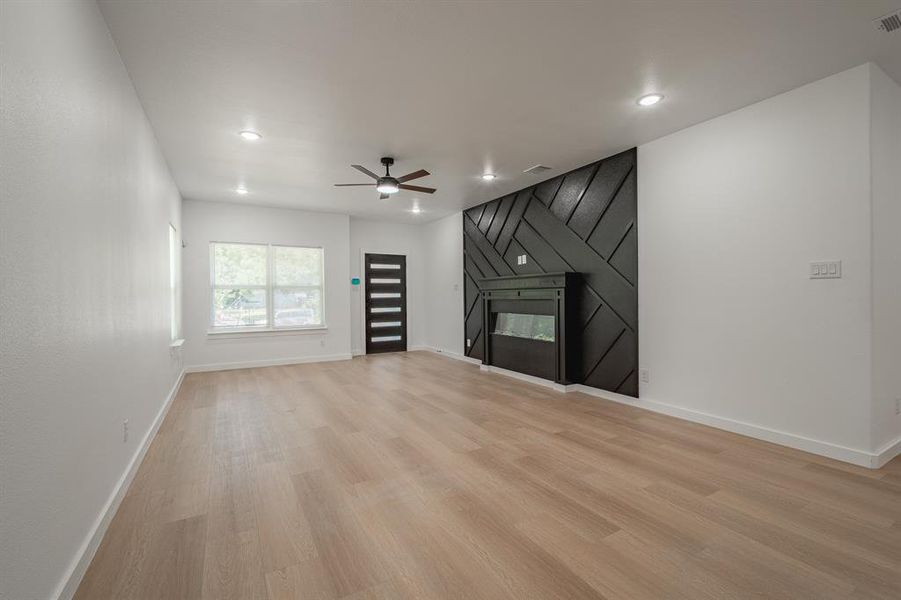 Unfurnished living room featuring ceiling fan, light wood-style floors, recessed lighting, and a fireplace Unfurnished living room featuring ceiling fan, light wood-style floors, recessed lighting, and a fireplace